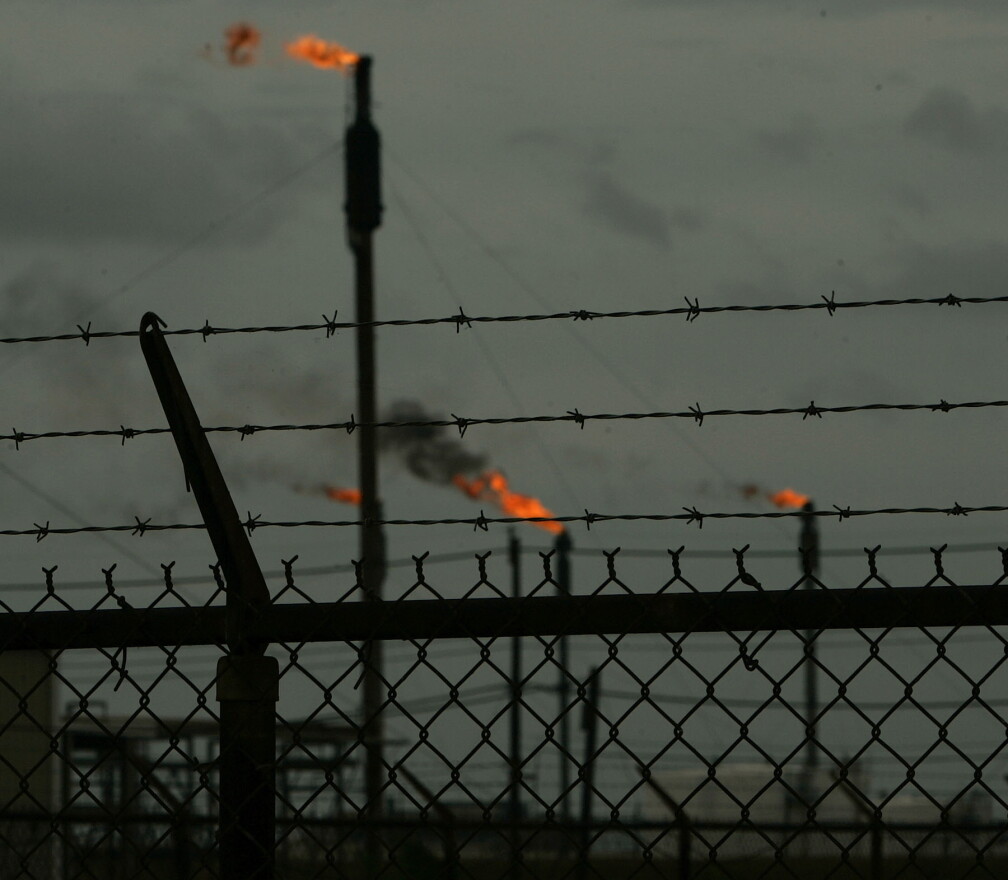 Oil refinery torches burn behind barbed wire in Beaumont, Tex. 